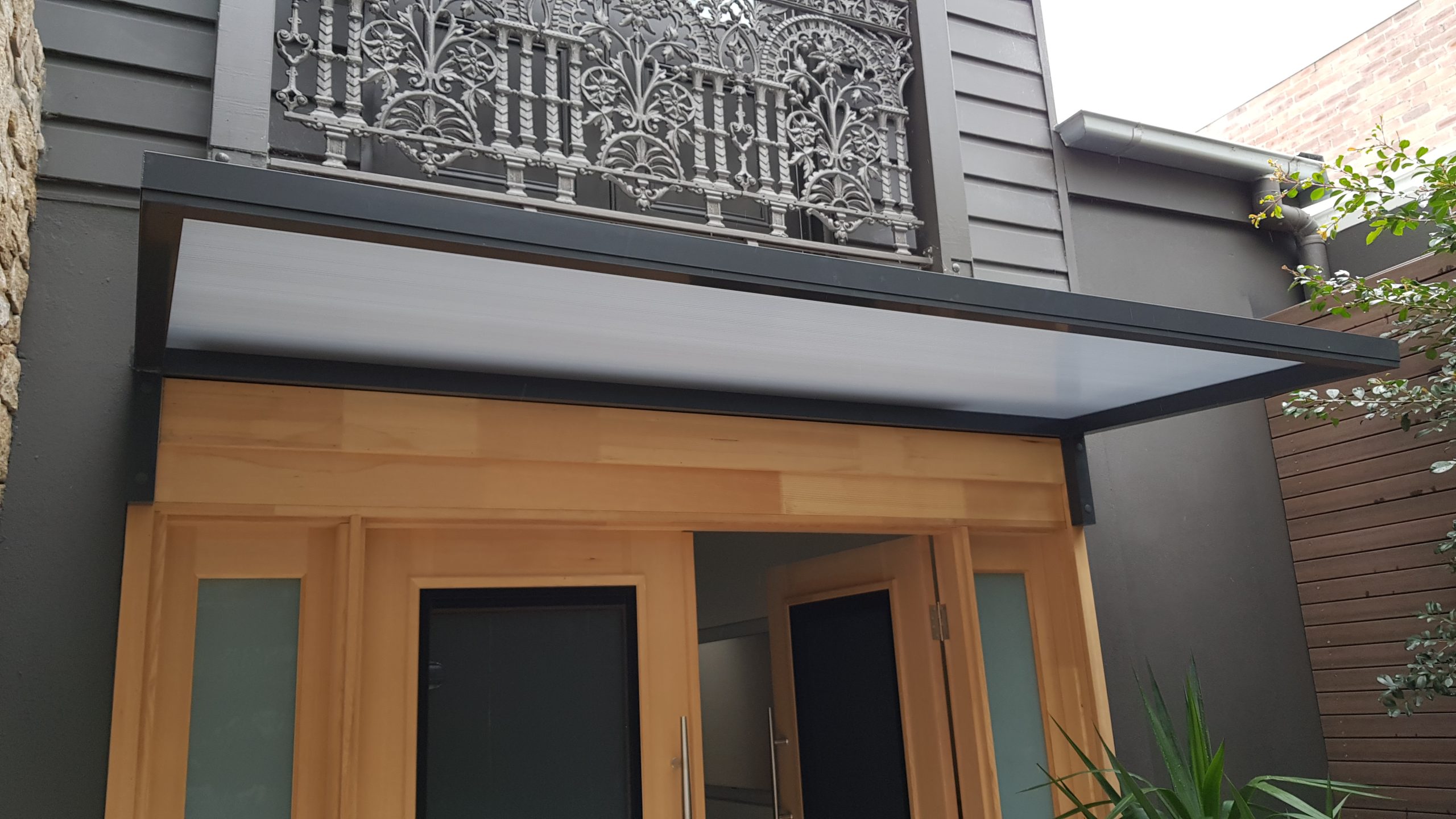 Slimline 50 aluminium window and door awning installed above timber-framed openings with a slim flat-profile blade