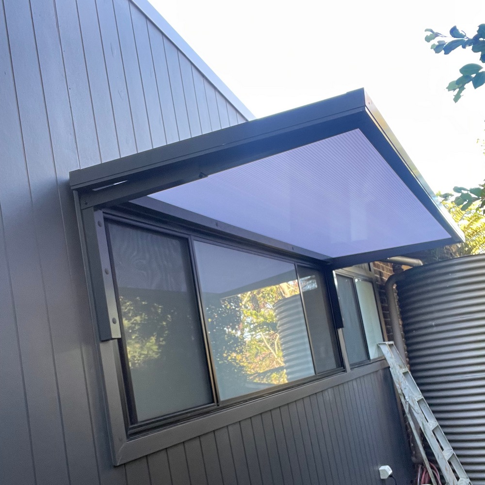 Slimline 50 cantilever aluminium awning mounted to a window frame on a timber stud wall with polycarbonate infill