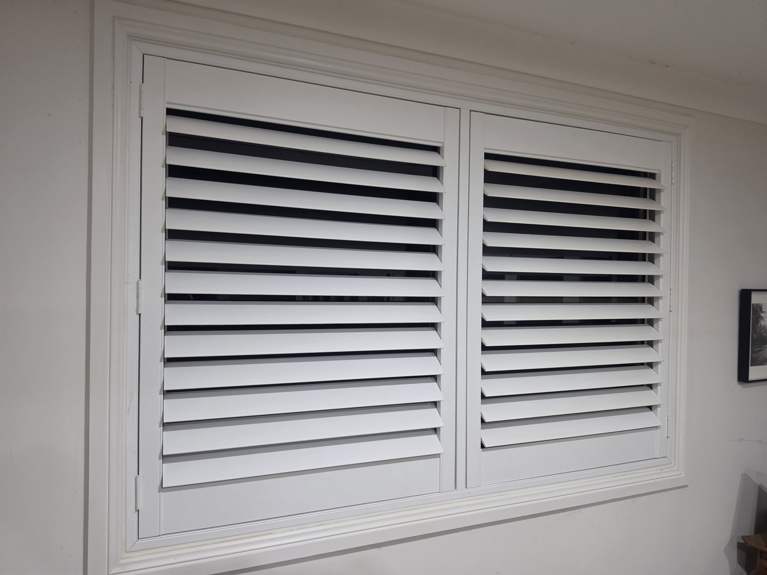 louvres vs shutters – white plantation shutters fitted inside a window of an Australian home